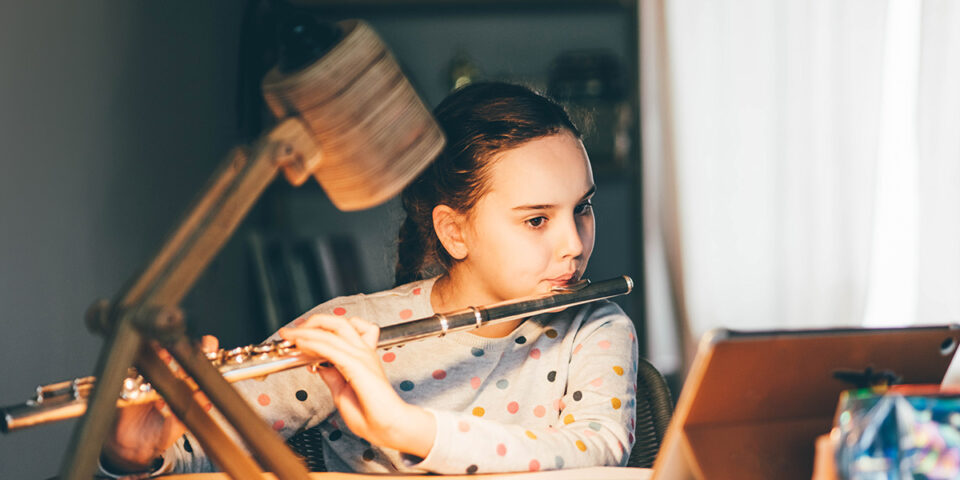 A young girl practicing online music lessons.