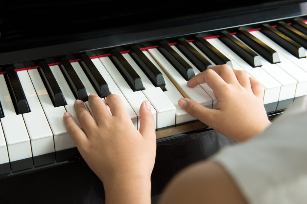 Close up of little girl playing music on piano